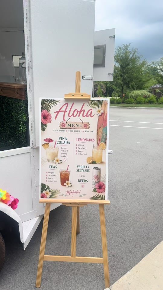 A printed Aloha menu on a wooden easel beside the trailer